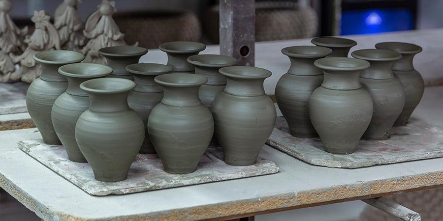 Vasi in ceramica verdi fatti a mano di Caltagirone in fase di asciugatura su tavoli da laboratorio