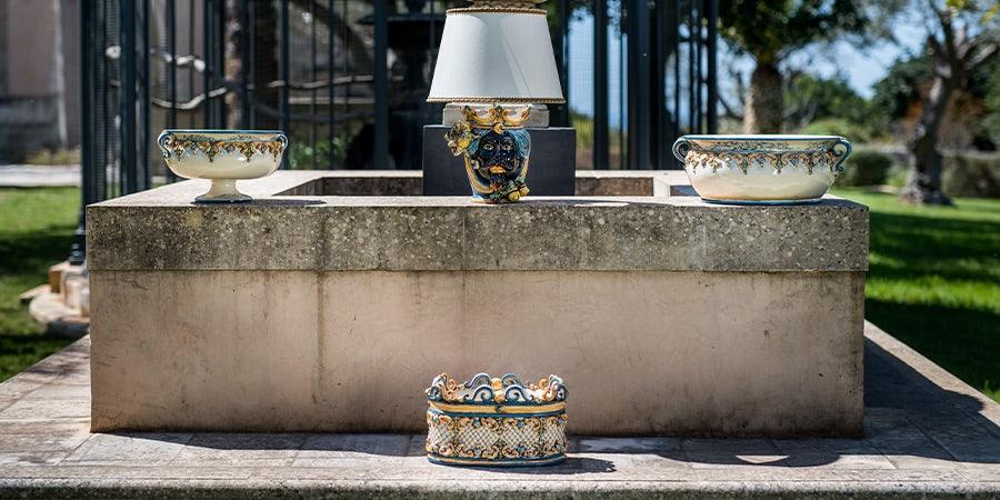 Ceramiche Caltagirone fatti a mano esposte all'aperto, vasi e lampada decorati artigianalmente.