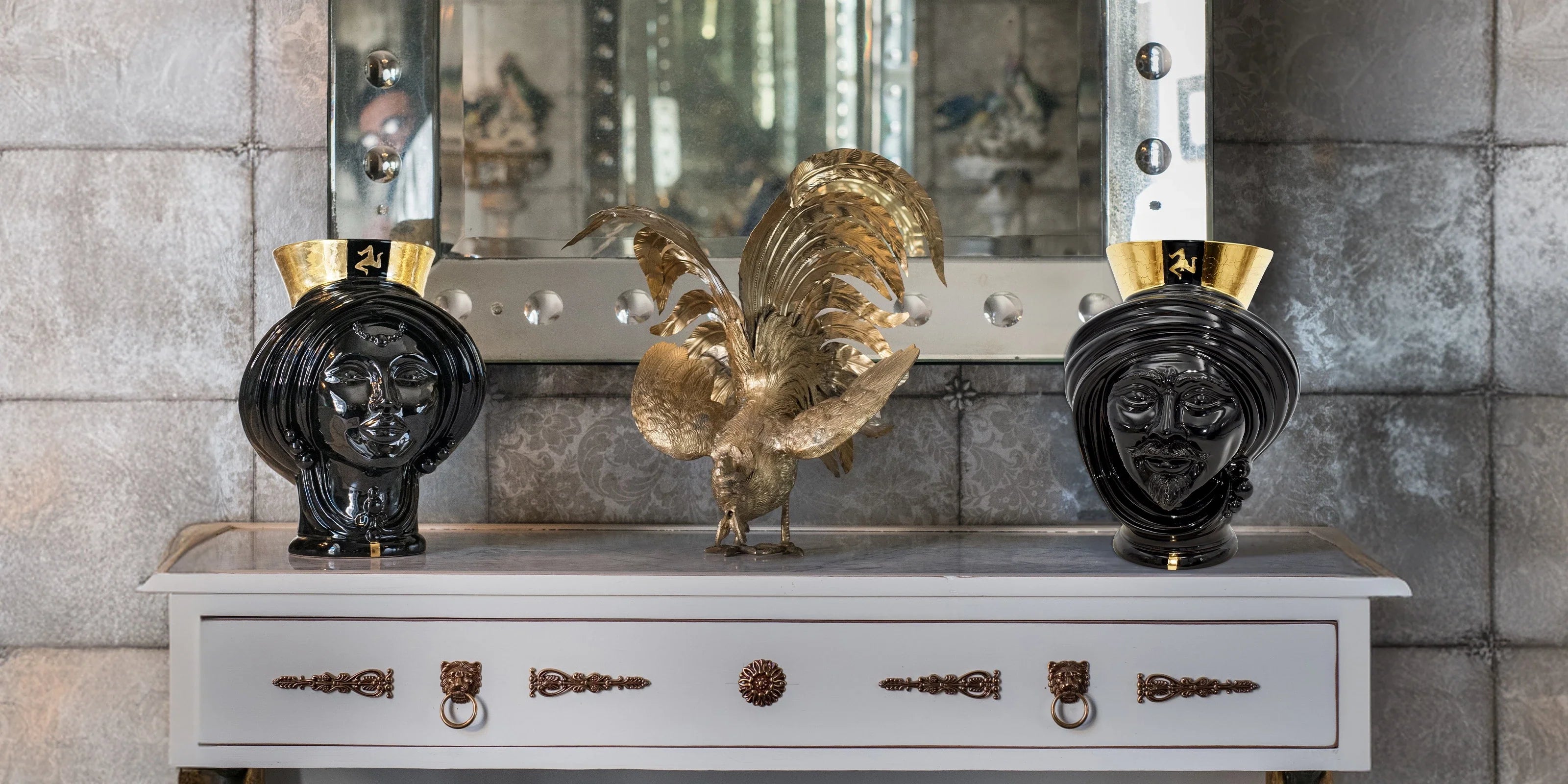 Teste di moro neri con dettagli oro, ceramiche Caltagirone fatti a mano su mobile elegante.