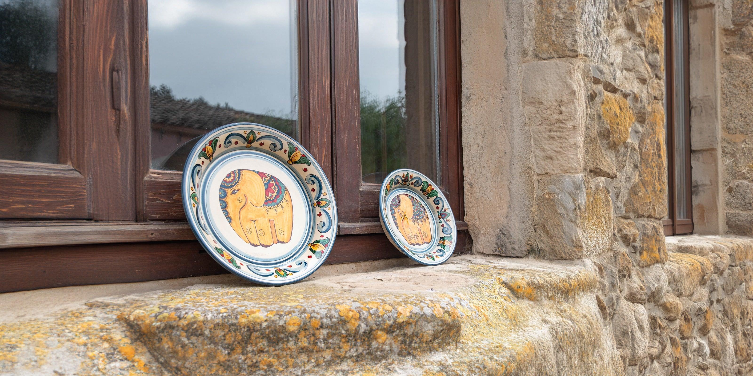 Piatti ceramiche caltagirone fatti a mano con elefanti decorativi su davanzale rustico