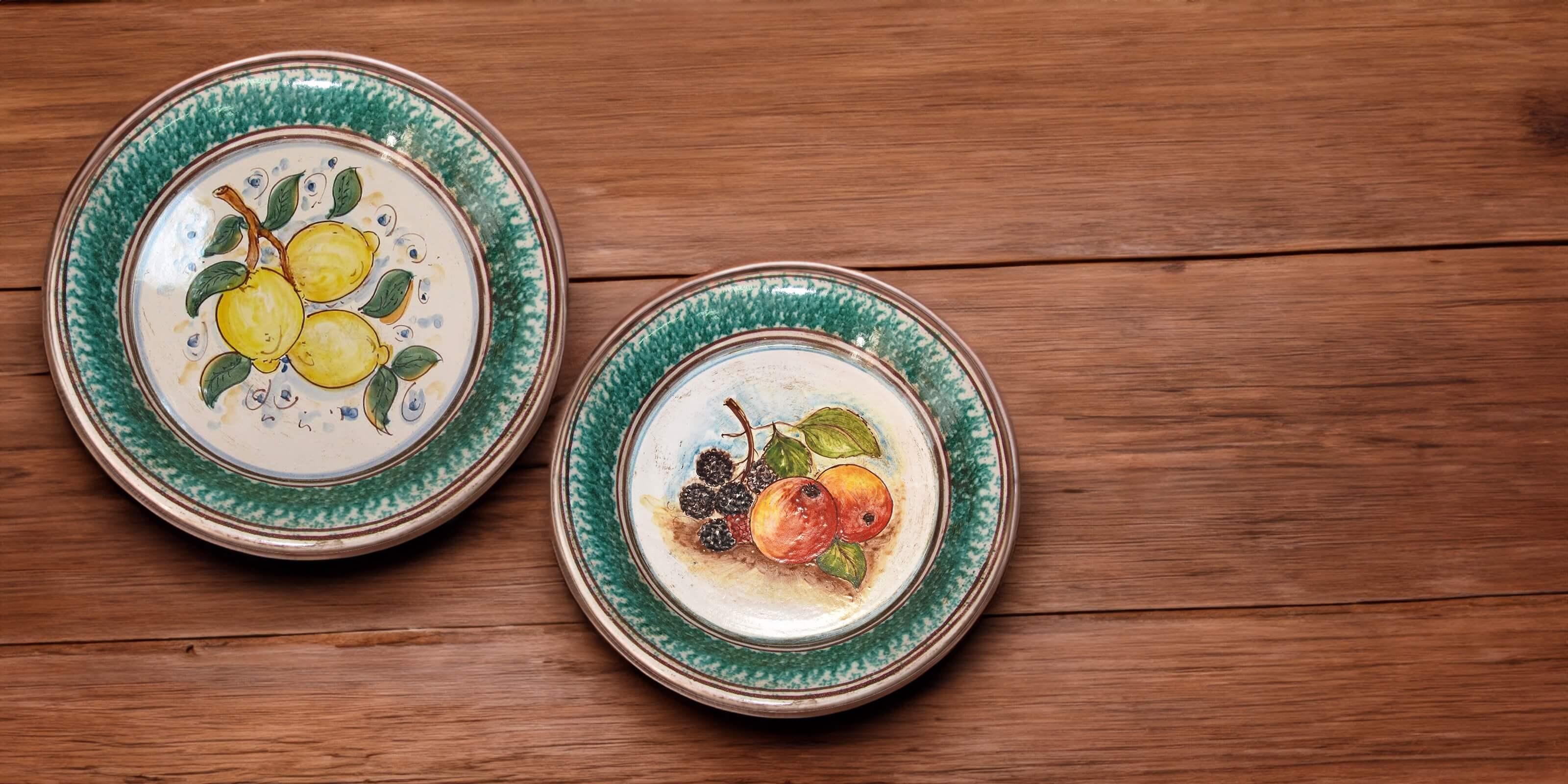 Piatti ceramiche Caltagirone Sofia decorati a mano con frutta su tavolo in legno