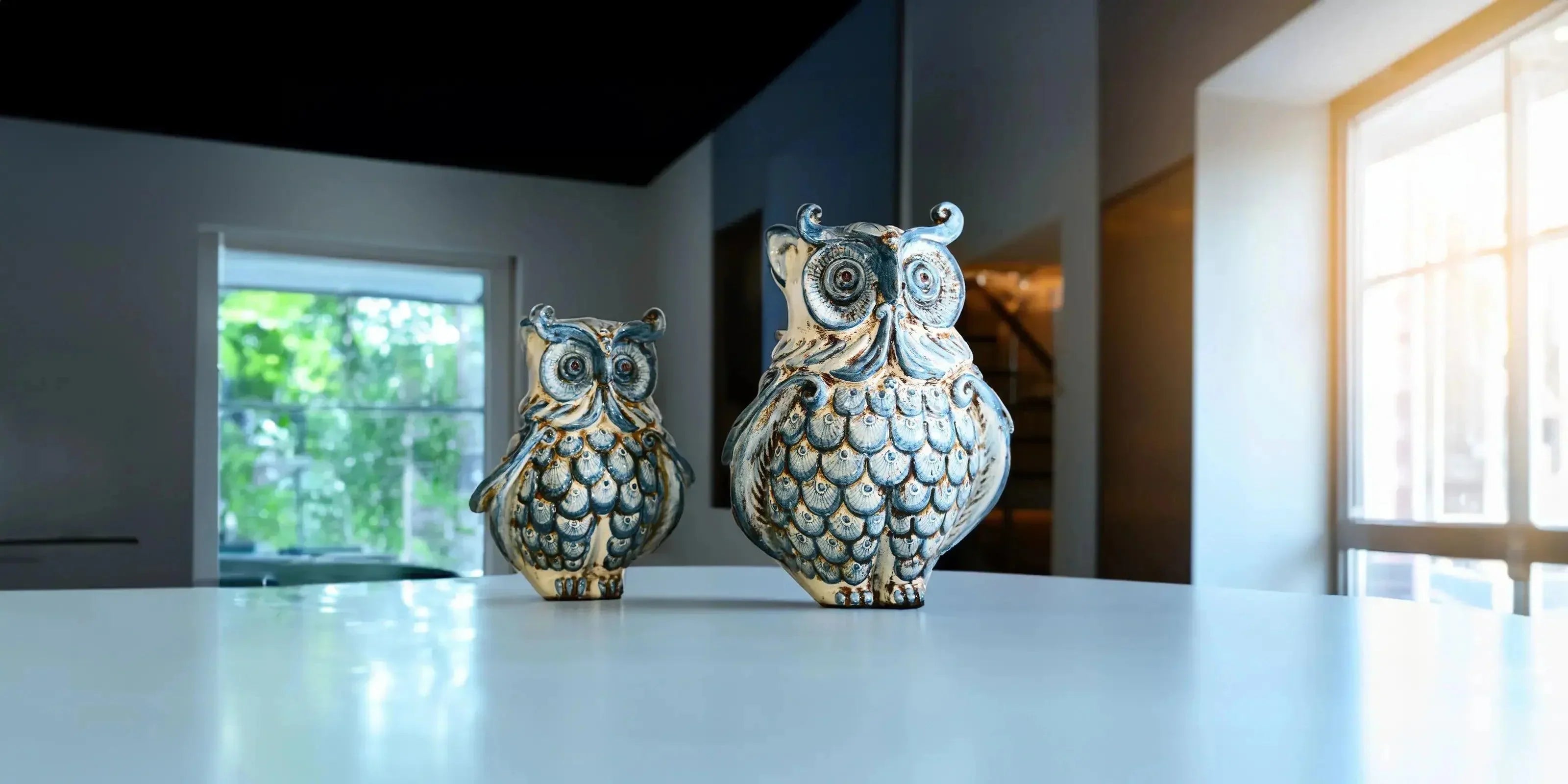 Gufi ceramiche di Caltagirone fatti a mano con dettagli blu e beige su tavolo bianco in ambiente illuminato