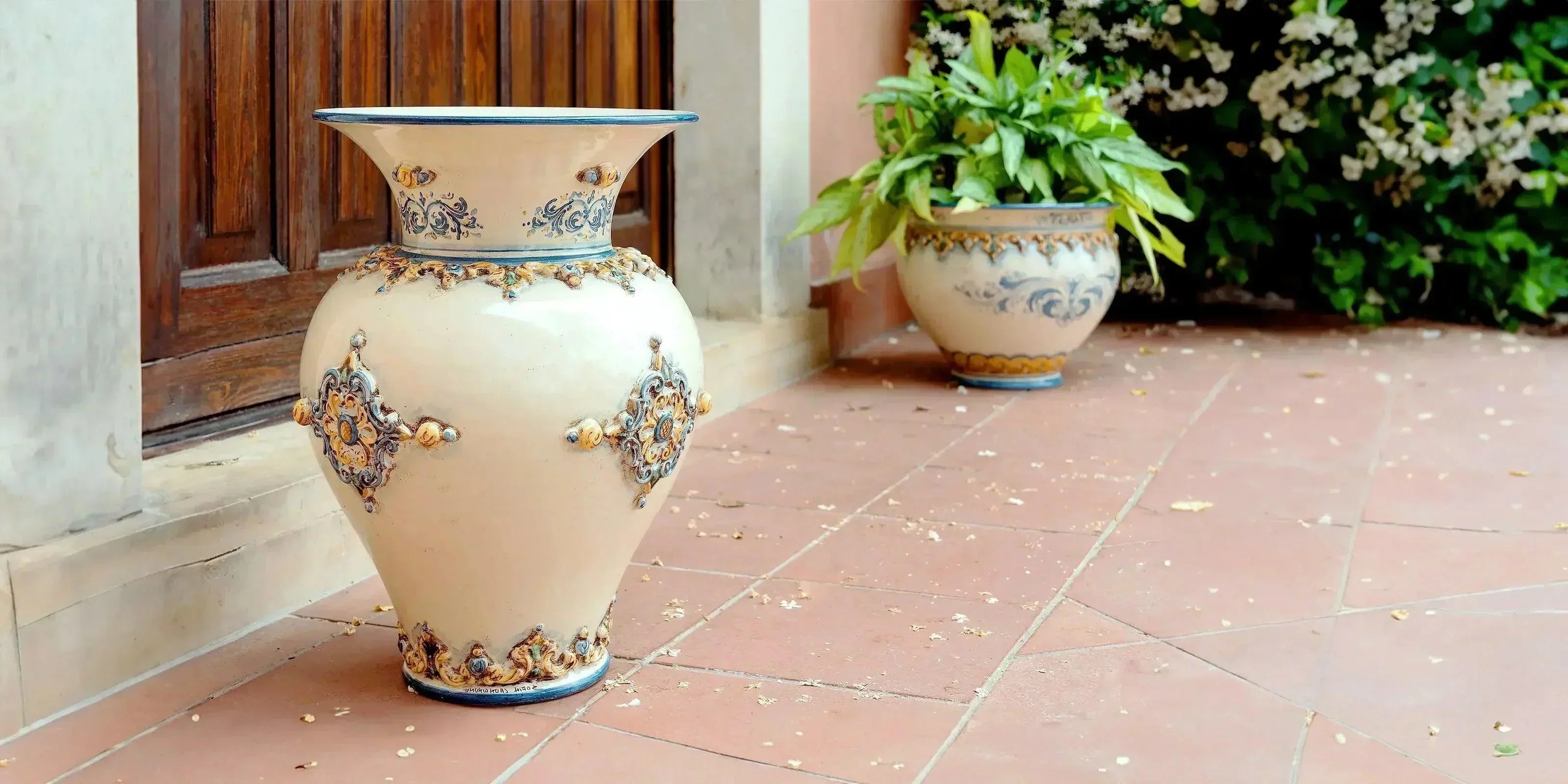 Portaombrelli e vaso in ceramiche Caltagirone fatti a mano con decori blu e arancioni su terrazzo esterno