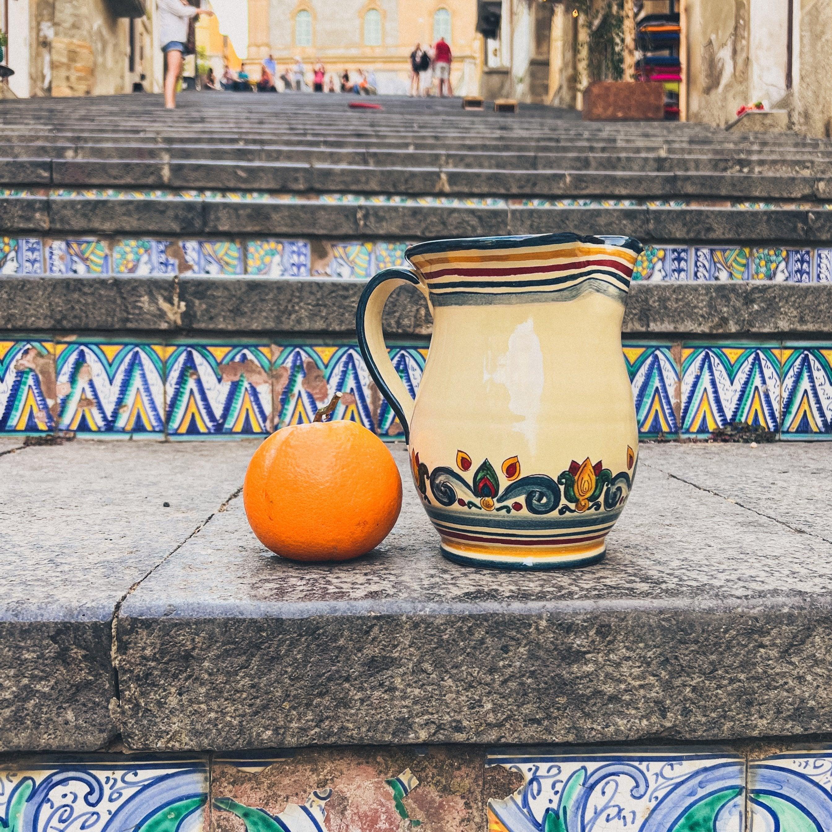 Brocca decorata ceramiche Caltagirone fatti a mano accanto a un'arancia su scala siciliana