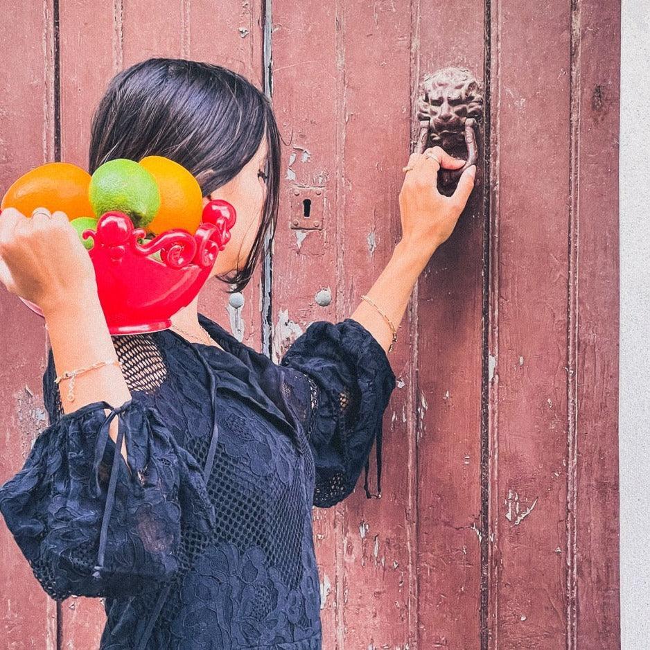 Donna con centrotavola rosso ceramiche caltagirone fatti a mano davanti a porta antica