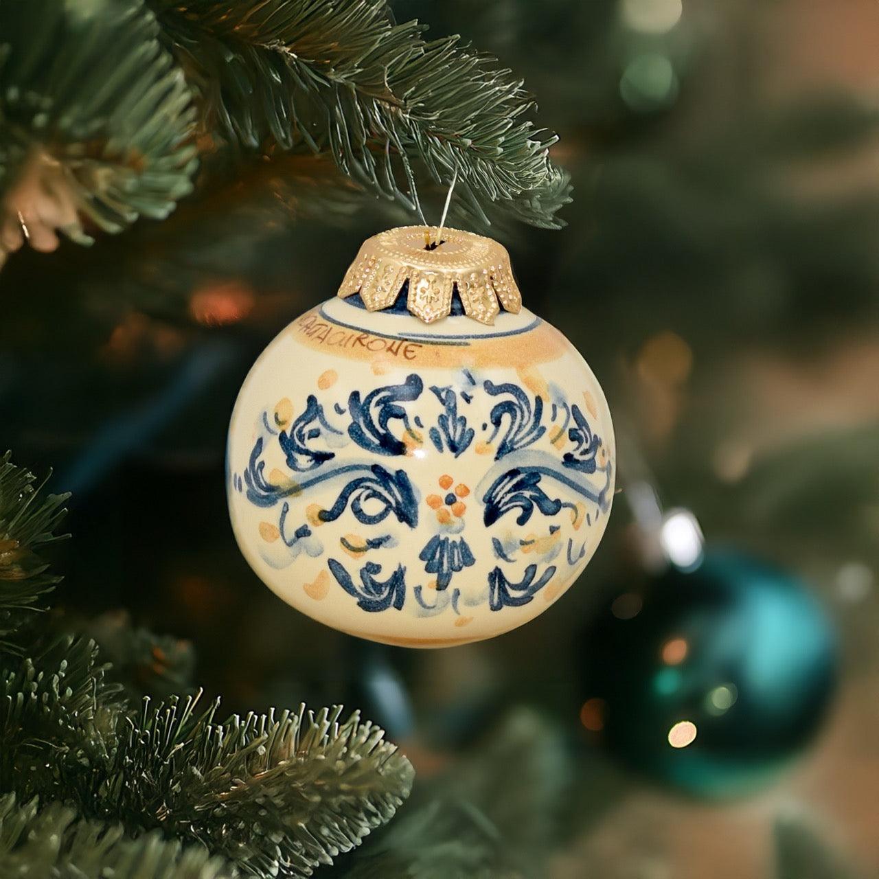 Pallina natalizia in ceramica di Caltagirone fatta a mano con decorazioni blu e arancio su albero di Natale