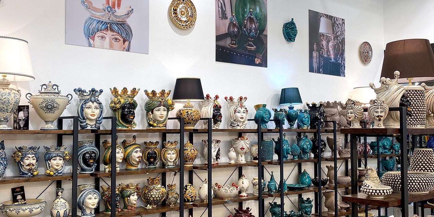 Esposizione di ceramiche Caltagirone fatti a mano, teste di moro e vasi artigianali colorati.