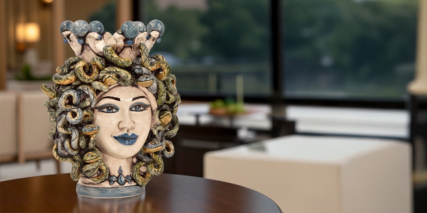 Testa di Medusa in ceramica fatta a mano di Caltagirone con serpenti verdi su tavolo in interno moderno