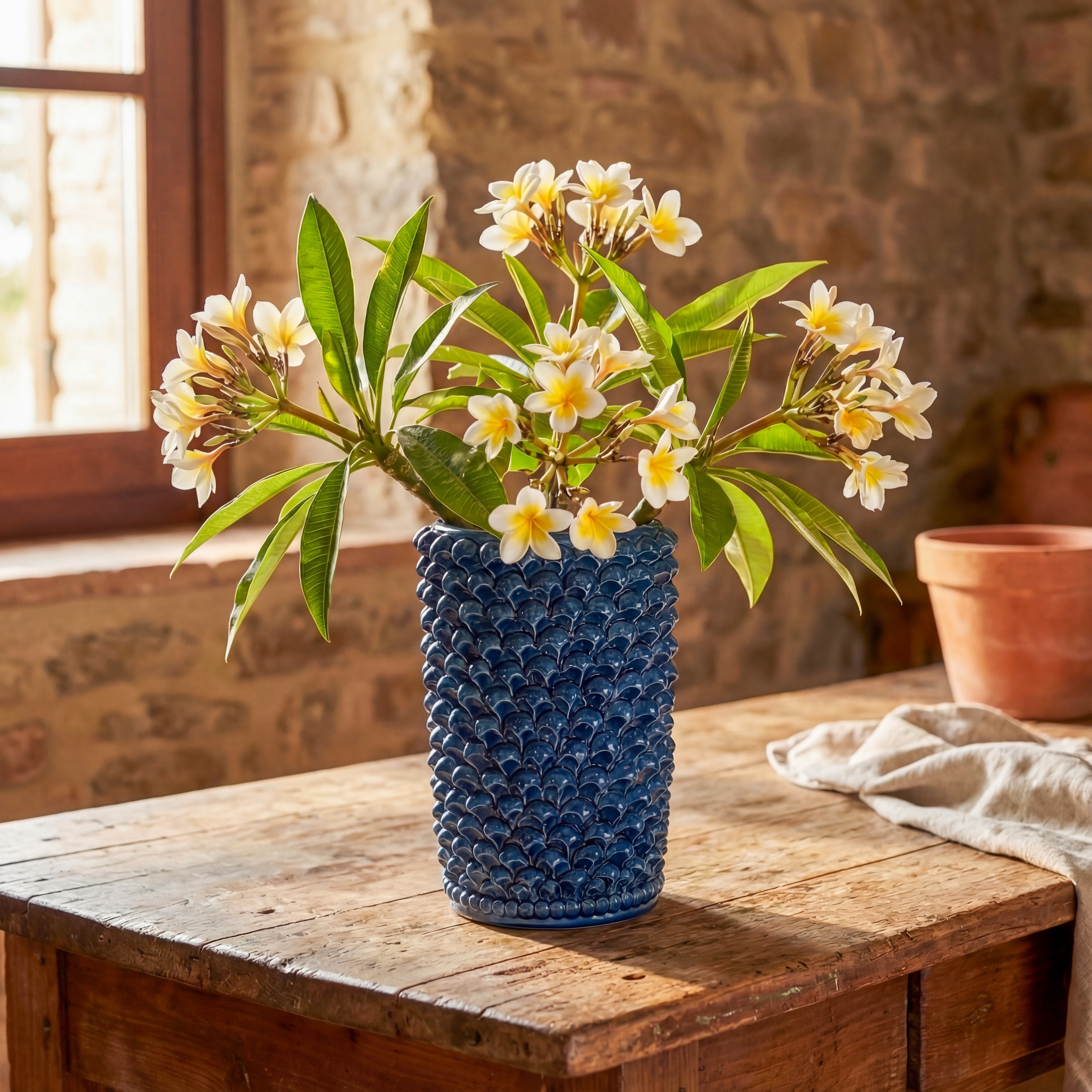 Vaso in ceramica di Caltagirone fatti a mano blu su tavolo rustico con fiori bianchi